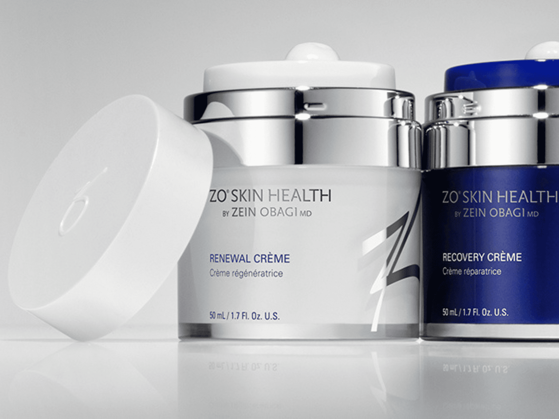 ZO Skin Health Renewal and Recovery Creams in sleek containers on a reflective surface.