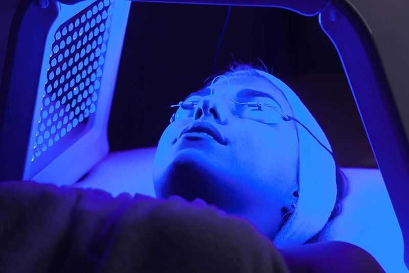 Person undergoing blue light therapy treatment for skincare rejuvenation.