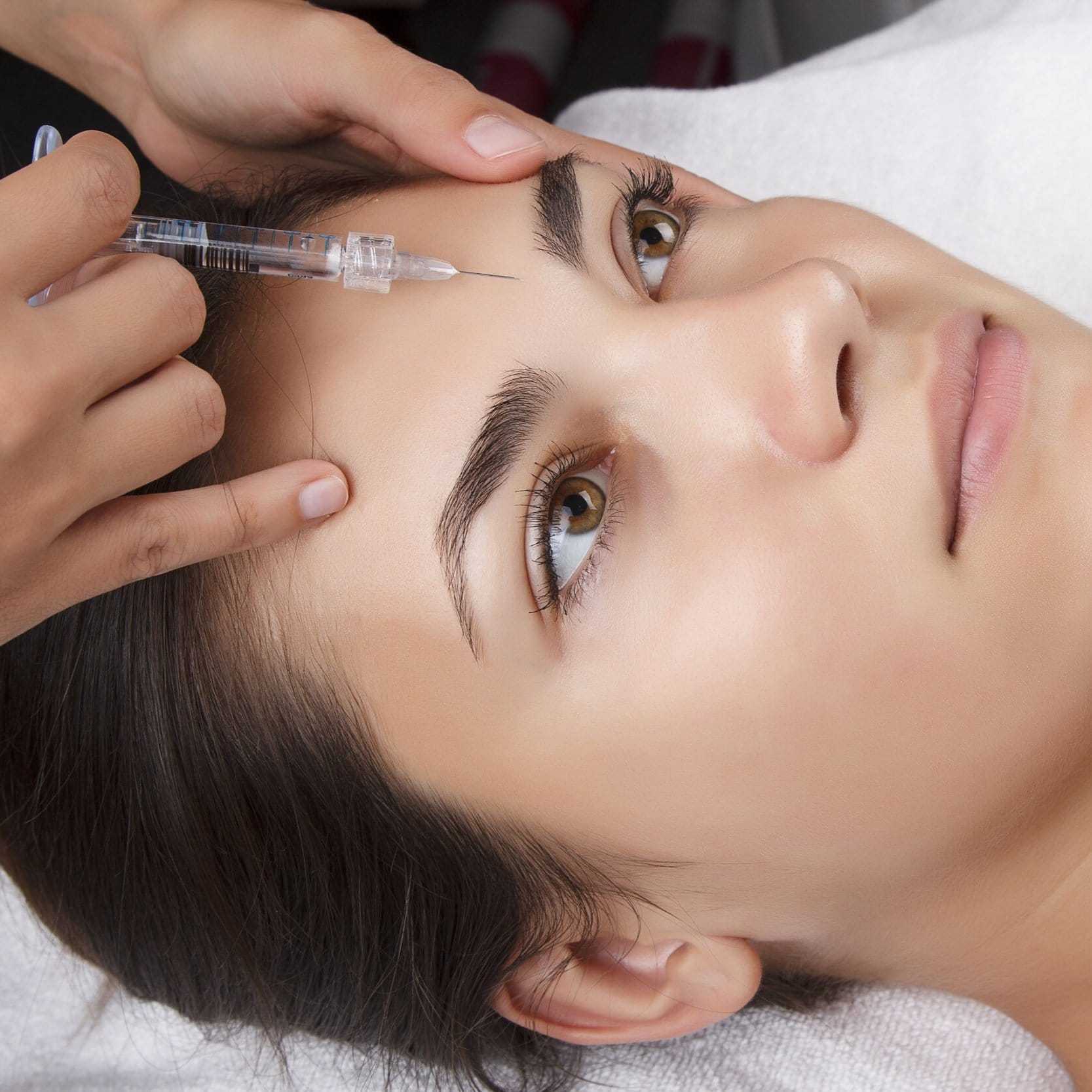 Woman receiving a cosmetic injection in forehead at a skincare clinic.